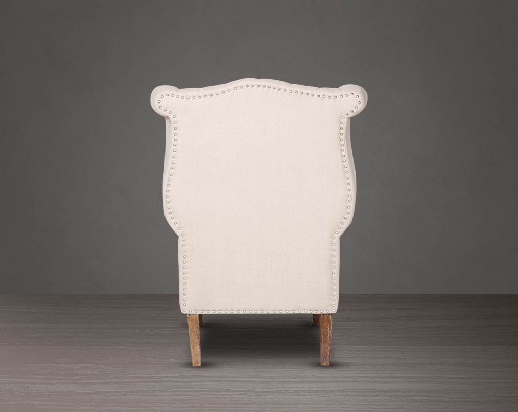 Wing arm chair back upholstered in fabric with tufted back and stainless steel rivets and oak wood legs