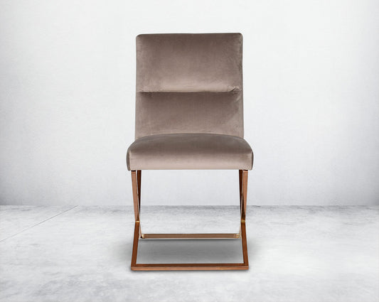 Dining chair upholstered in fabric with rose gold plated stainless steel legs in a cross design.