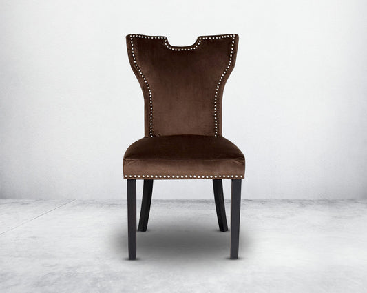 Dining chair front upholstered in fabric with legs in wood. Stainless steel decorative ring at the back with stainless steel rivets.