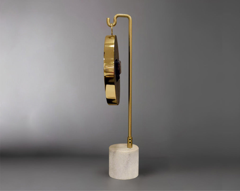 Round clock suspended on a hook in glossy gold & white marble base with back view