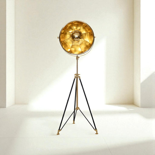 Vintage-style floor lamp with gold shade and black tripod base on a white background