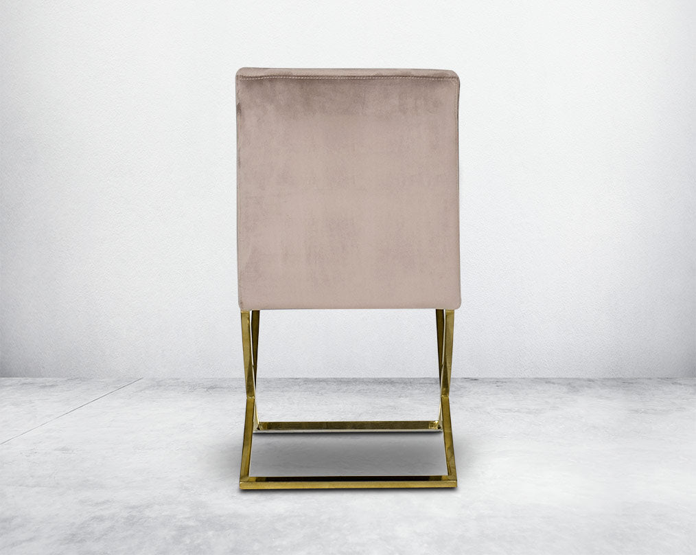 Dining chair with back upholstered in fabric with gold plated stainless steel legs in a cross design.