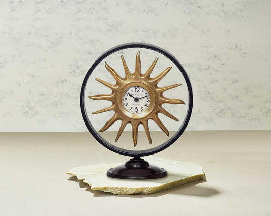 Round table clock in antique matt brass in sun ray design motif.