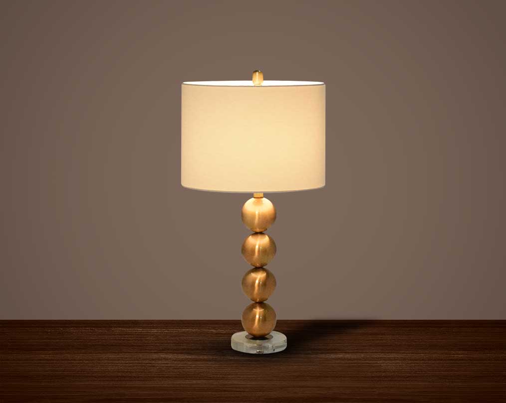 Table lamp with metallic gold and glass decorative base with translucent fabric shade.