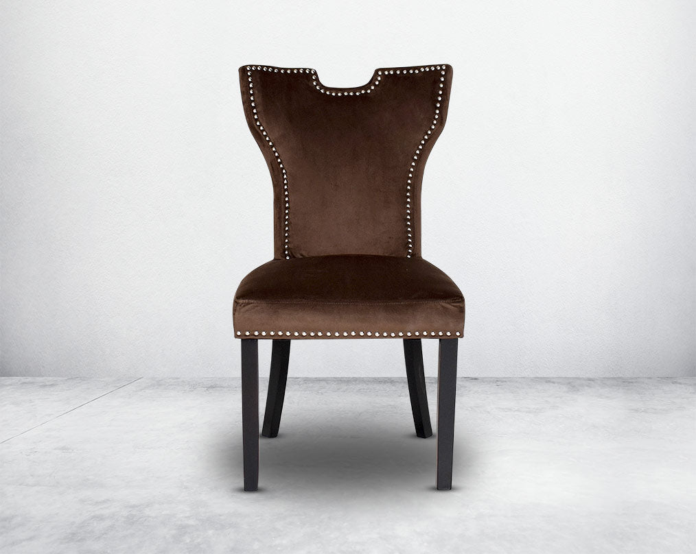 Dining chair  front upholstered in fabric with legs in wood. Stainless steel decorative ring at the back with stainless steel rivets.