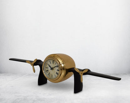 This unique vintage airplane propeller table clock comes with the clock in the center of the wings. This antique clock is made out of brass in antique matt finish. It has a white dial with Roman Numerals for a vintage look. This is a great statement piece