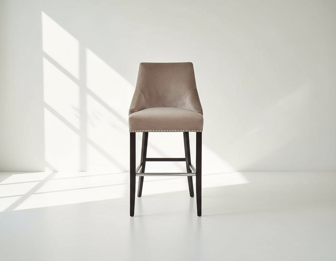 Bar chair upholstered in fabric with buttoned tufted back and silver rivets, the stool has a stainless steel front bar as a foot rest with legs in dark vintage brown wood front view 