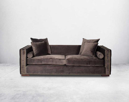 3 seater sofa set upholstered in fabric with gold rivets on the arms and front and tufted on the sides front view