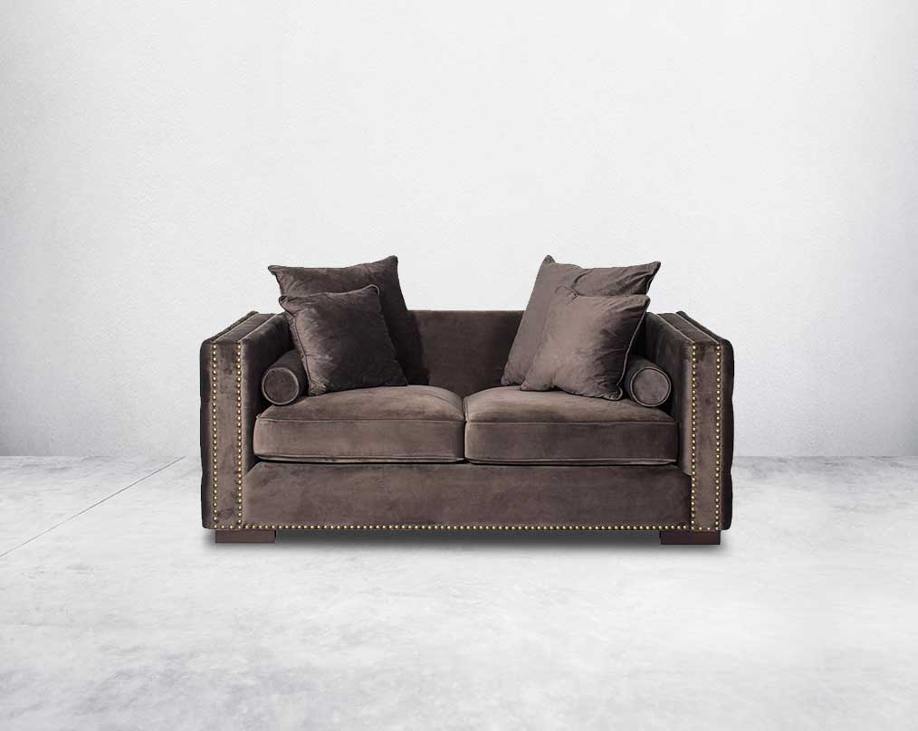 2 seater sofa set upholstered in fabric with gold rivets on the arms and front and tufted on the sides front view