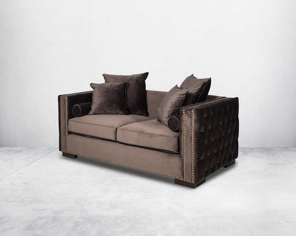 2 seater sofa set upholstered in fabric with gold rivets on the arms and front and tufted on the sides side view