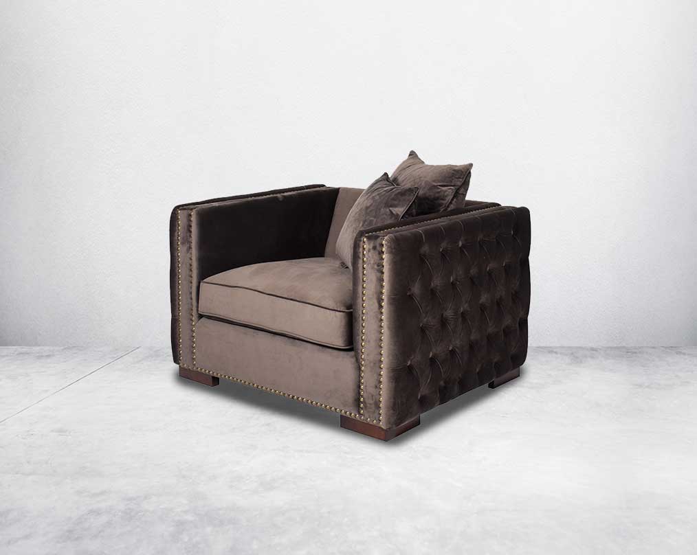 1 seater sofa set upholstered in fabric with gold rivets on the arms and front and tufted on the sides side view