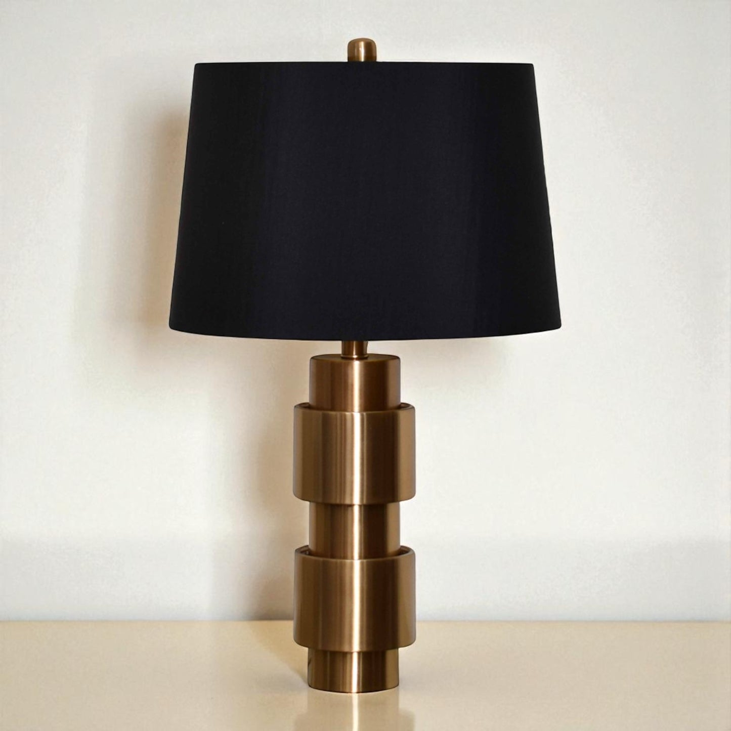 Table lamp with black shade and bronze base on a neutral background