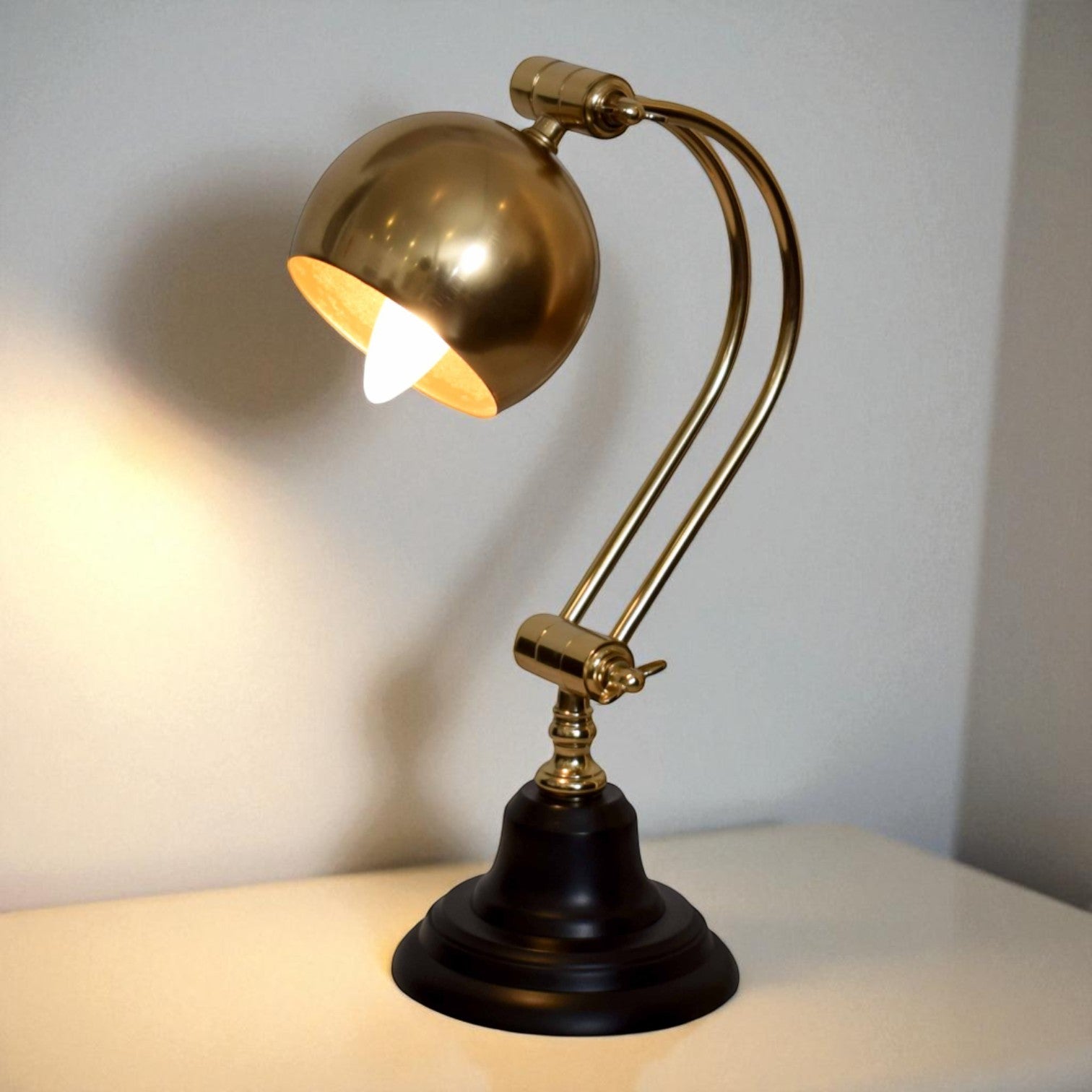 Gold desk lamp with black base on a white surface