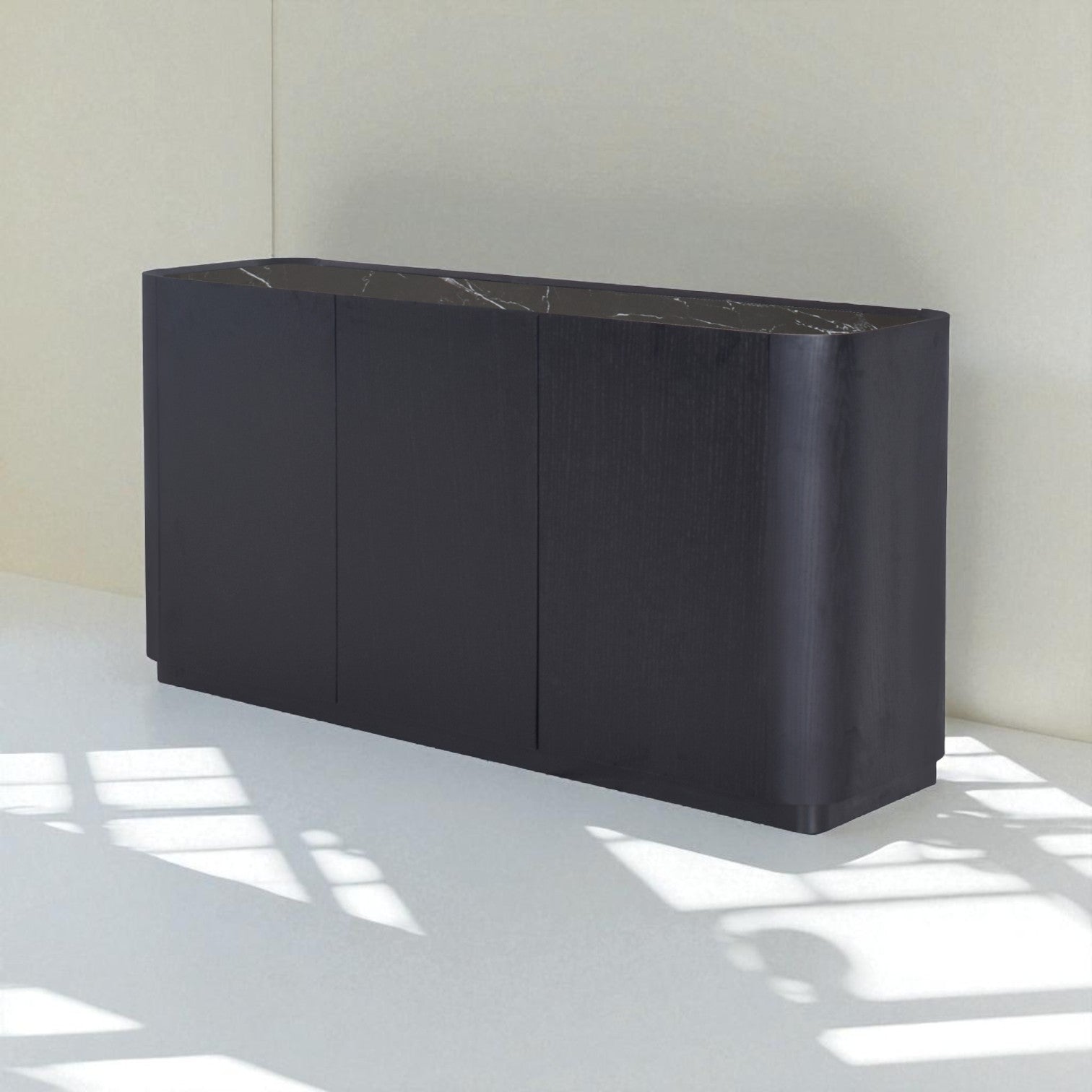 Black sideboard with marble top on a white floor and wall