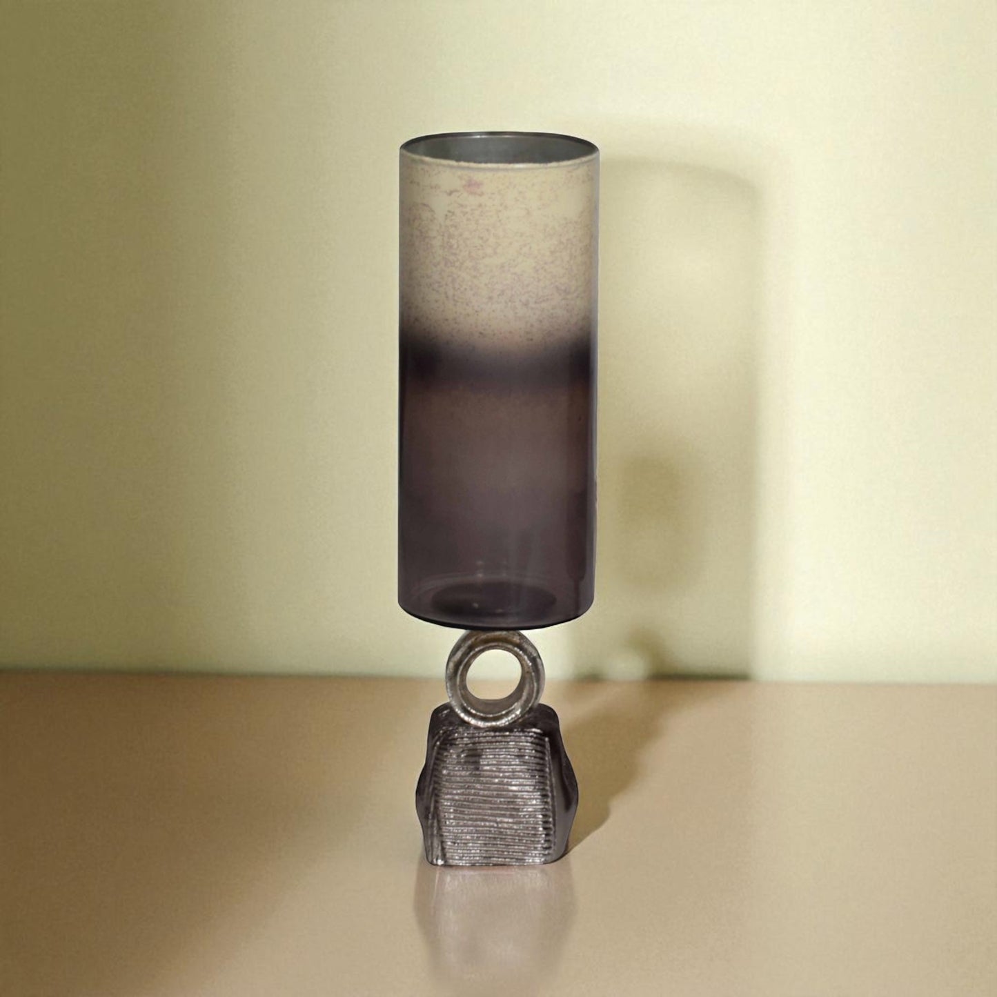 Decorative lamp with a cylindrical shade and metallic base on a beige surface.