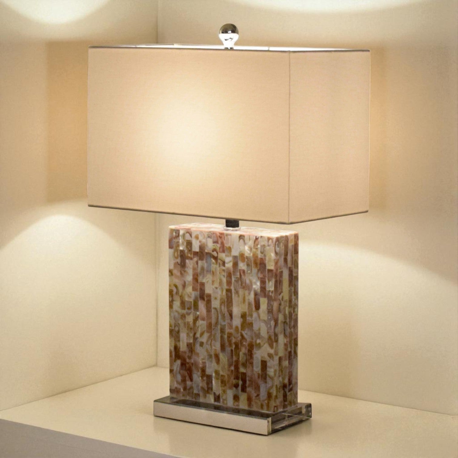 Table lamp with mosaic base and beige rectangular shade on a neutral background