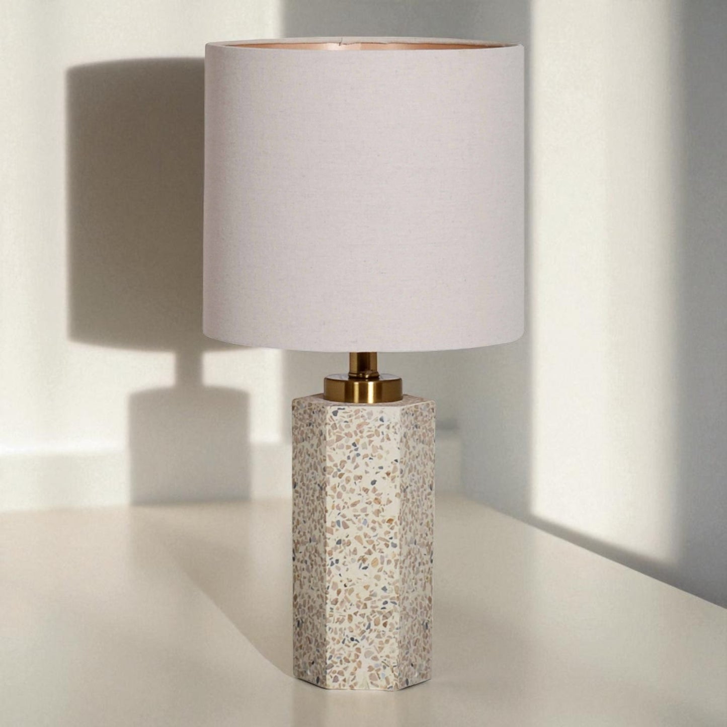 Table lamp with terrazzo base and white shade on a light surface.