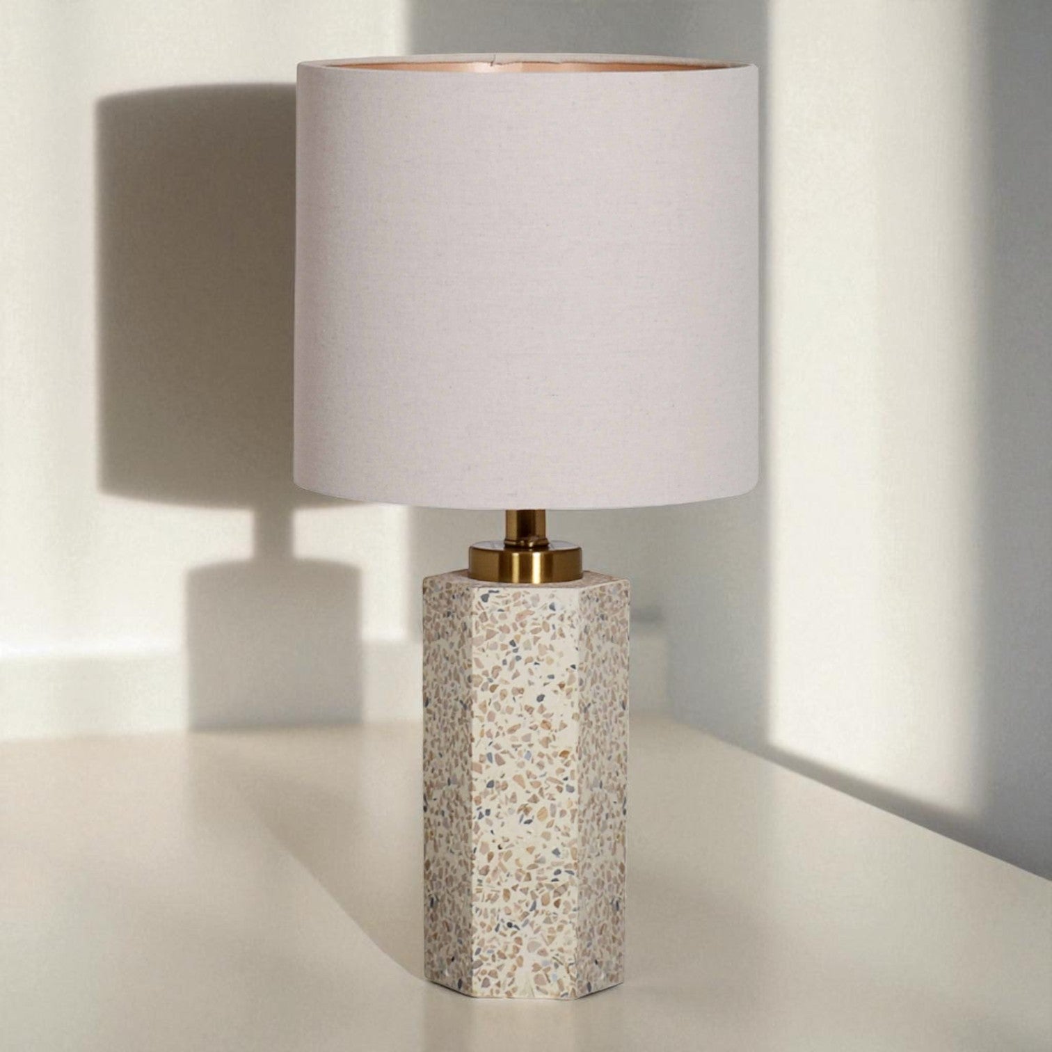 Table lamp with terrazzo base and white shade on a light surface.