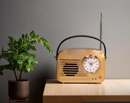 This unique retro table clock is sure to make a statement in any home. It is crafted in antique brass. Has a functional cock in vintage radio design with table and plant 