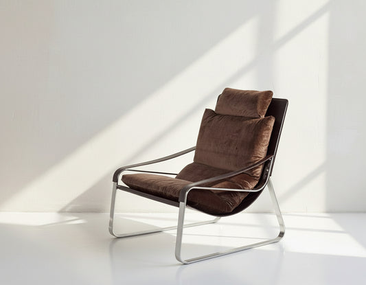 Leisure chair upholstered in fabric with high polished stainless steel frame.