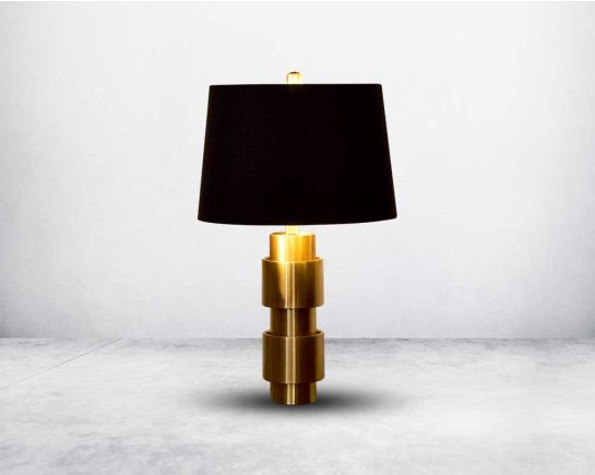 Table lamp in gold decorative geometrical base with black fabric translucent fabric shade.