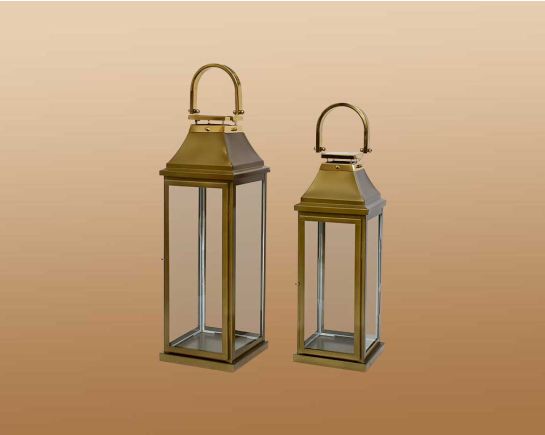 This lantern in modern classic style is crafted in Stainless steel finished in antique gold. It has clear glass & brass handles. This is a perfect mood setter enhancing any room with its glow. large 